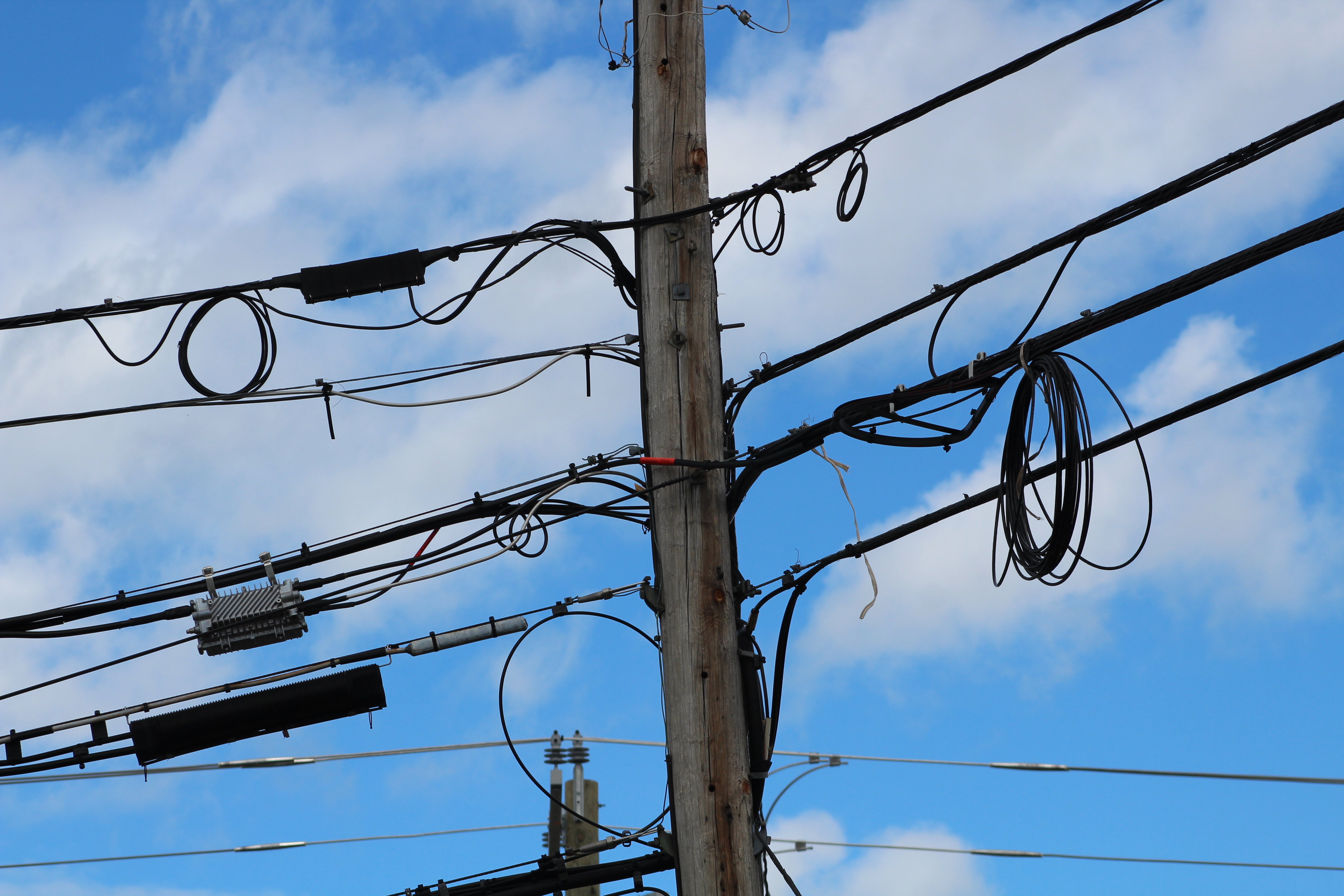A wooden telephone pole carrying overhead communications cables and network hardware